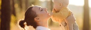 Portrait of young attractive family with little baby son, posing in beautiful autumn pine forest at sunny day. Handsome man and  his pretty brunette wife